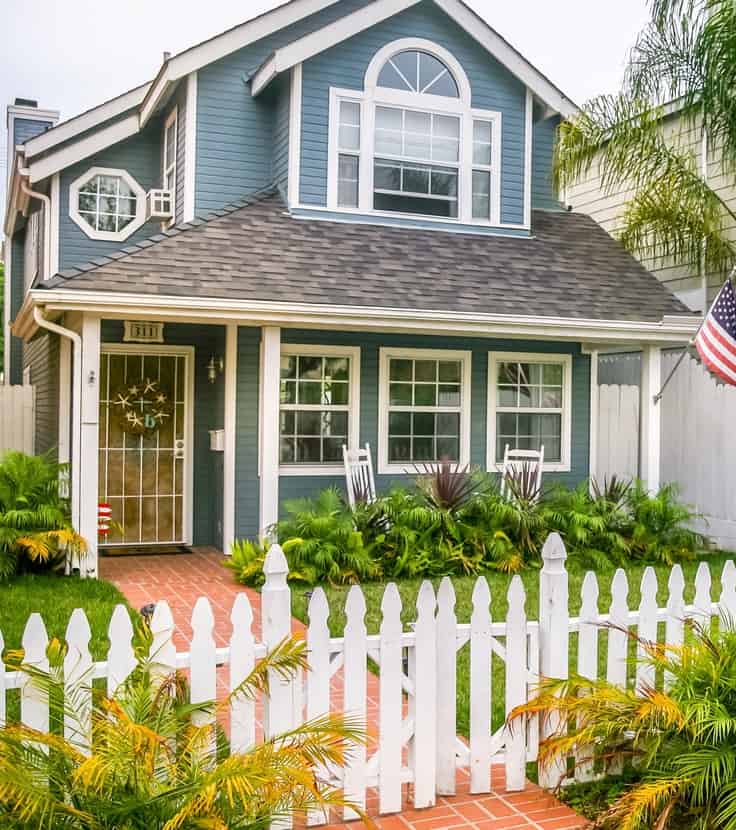 Two storey blue house with white fence